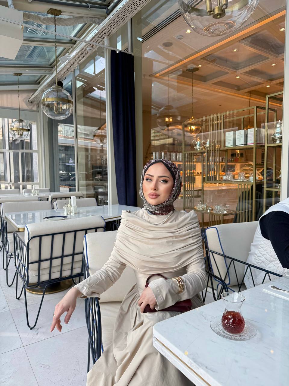 Elegante beige maxi-jurk met drape details aan de voorzijde, lange mouwen en een flatterende pasvorm – ideaal voor een stijlvolle, bescheiden look