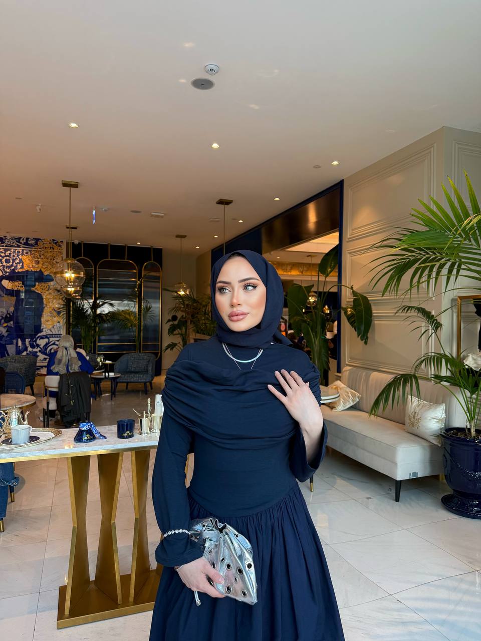 Elegante marine-blauw maxi-jurk met drape details aan de voorzijde, lange mouwen en een flatterende pasvorm – ideaal voor een stijlvolle, bescheiden look