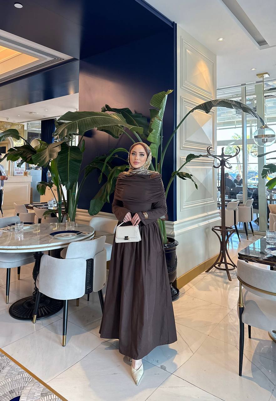 Elegante bruine maxi-jurk met drape details aan de voorzijde, lange mouwen en een flatterende pasvorm – ideaal voor een stijlvolle, bescheiden look