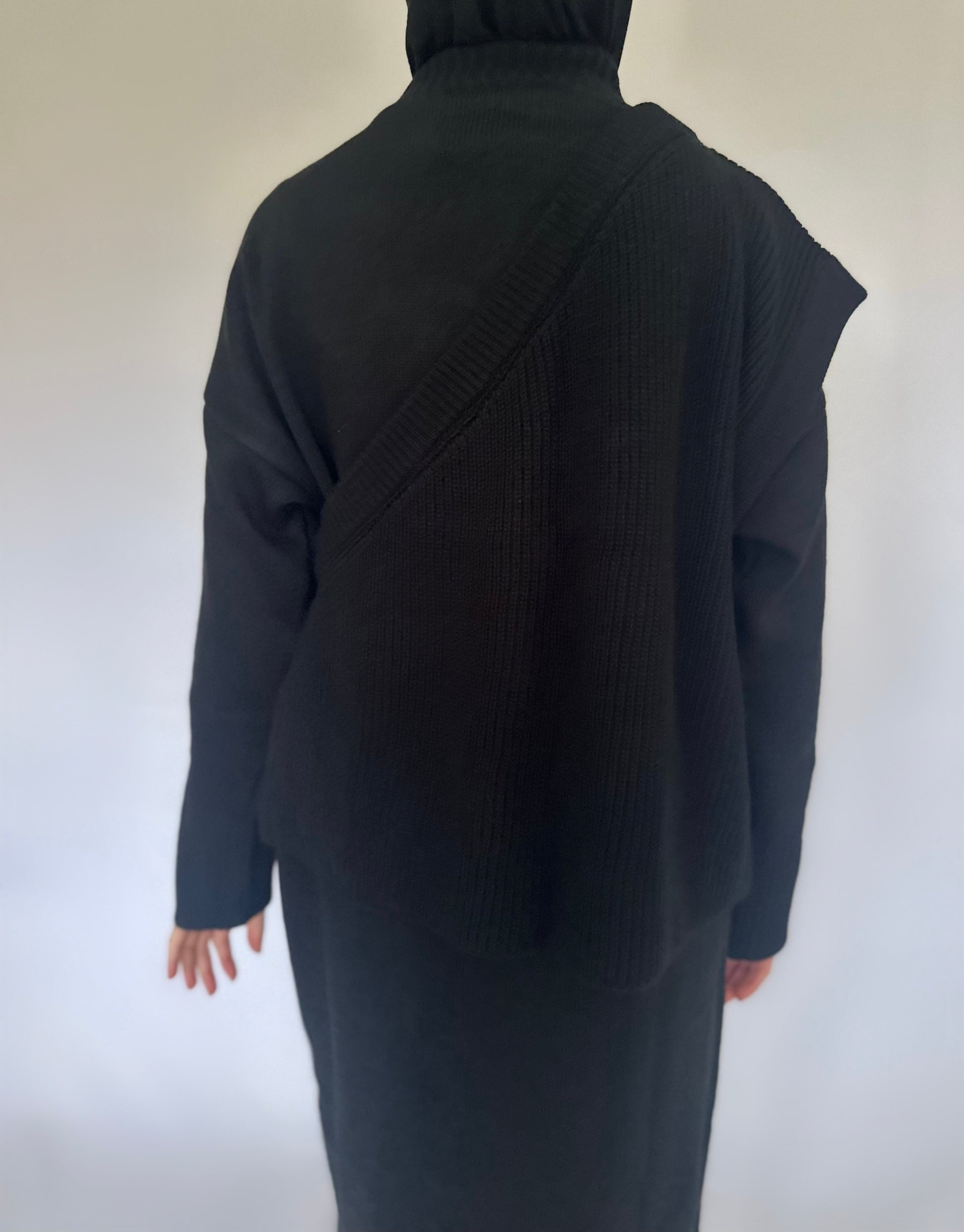 Zwart overslag tricot jurk van ByLiya, een 2-delige jurk met een maxi onderjurk en een wikkelstuk erboven voor een elegante en flatterende look.