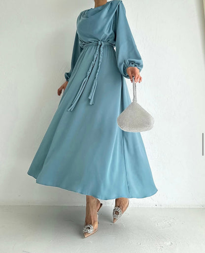 Model draagt de Liyana Dress in mint blauw – losvallende maxi jurk met rechte snit en strikceintuur in de taille