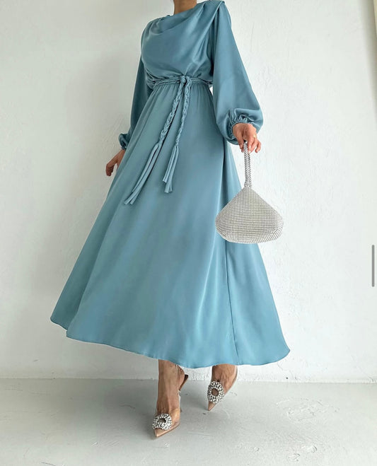 Model draagt de Liyana Dress in mint blauw – losvallende maxi jurk met rechte snit en strikceintuur in de taille