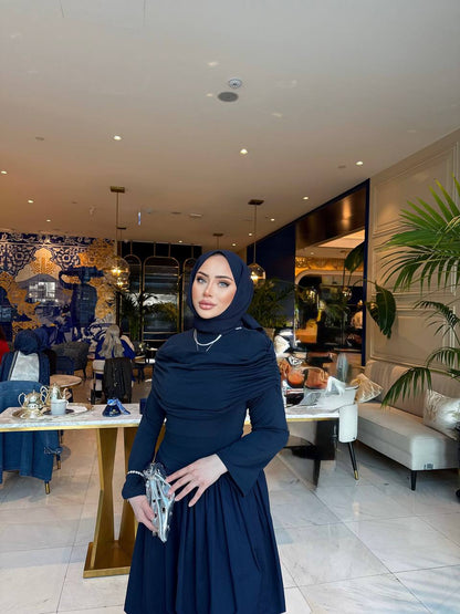 Elegante marine-blauw maxi-jurk met drape details aan de voorzijde, lange mouwen en een flatterende pasvorm – ideaal voor een stijlvolle, bescheiden look