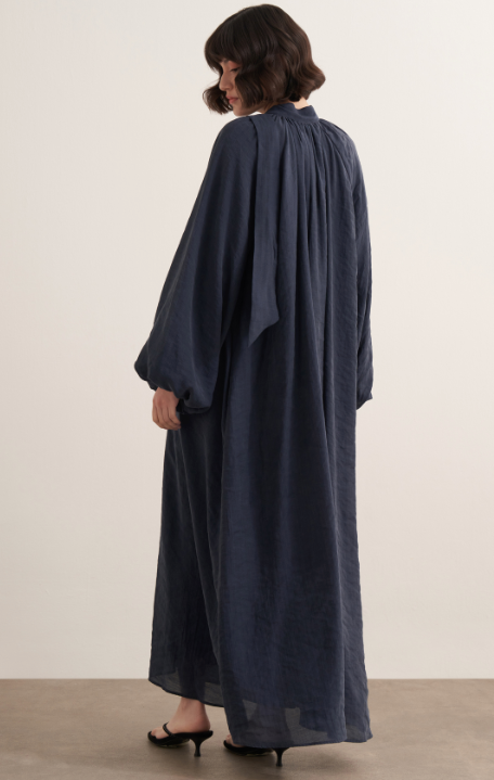 Maira maxi-jurk voor dames in marineblauw met verstelbaar taillelint, lange pofmouwen, hoge halslijn en soepelvallende stof, elegant modest fashion model.